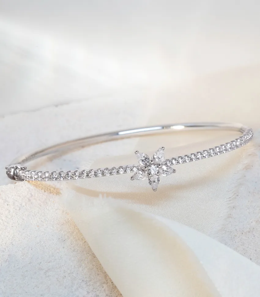 Silver bangle bracelet with a star-shaped diamond centerpiece, perfect for elegant occasions. 