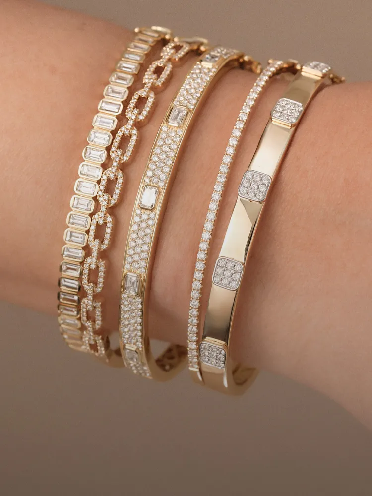 Four elegant diamond bracelets in gold, showcasing various designs and styles on a wrist. Shop at Bryan Jewelry in Prattville.