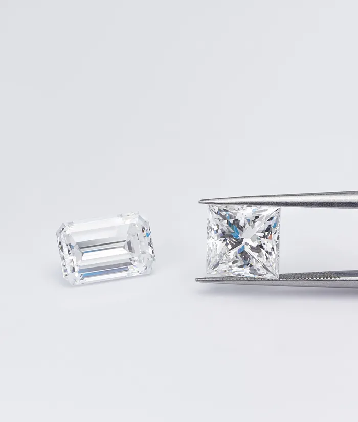 Two sparkling diamonds, one held by tweezers, showcasing bespoke luxury at Bryan Jewelry in Prattville.