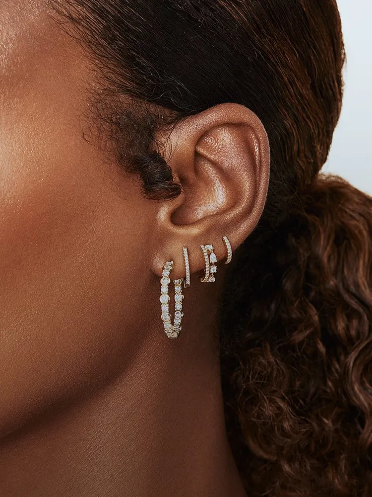 Close-up of a model's ear showcasing elegant diamond hoop earrings. Explore more at Bryan Jewelry, Prattville.