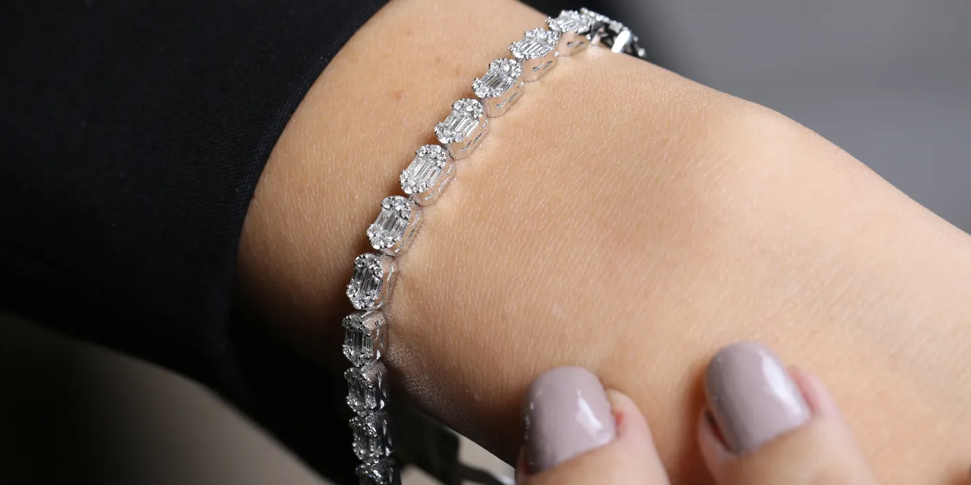 Elegant diamond tennis bracelet worn on a wrist, showcasing sparkling gems against a neutral background.