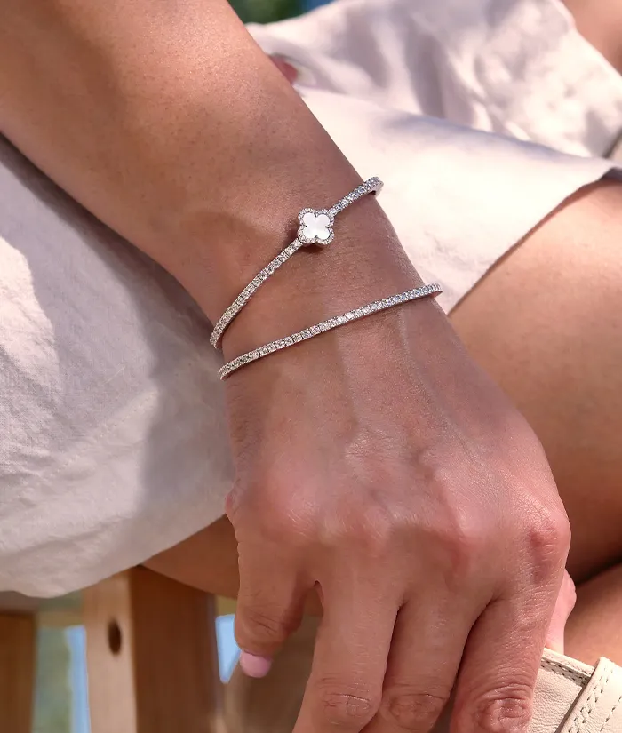 Elegant silver bracelets with a floral design and sparkling accents worn on a woman's wrist. Shop at Bryan Jewelry in Prattville
