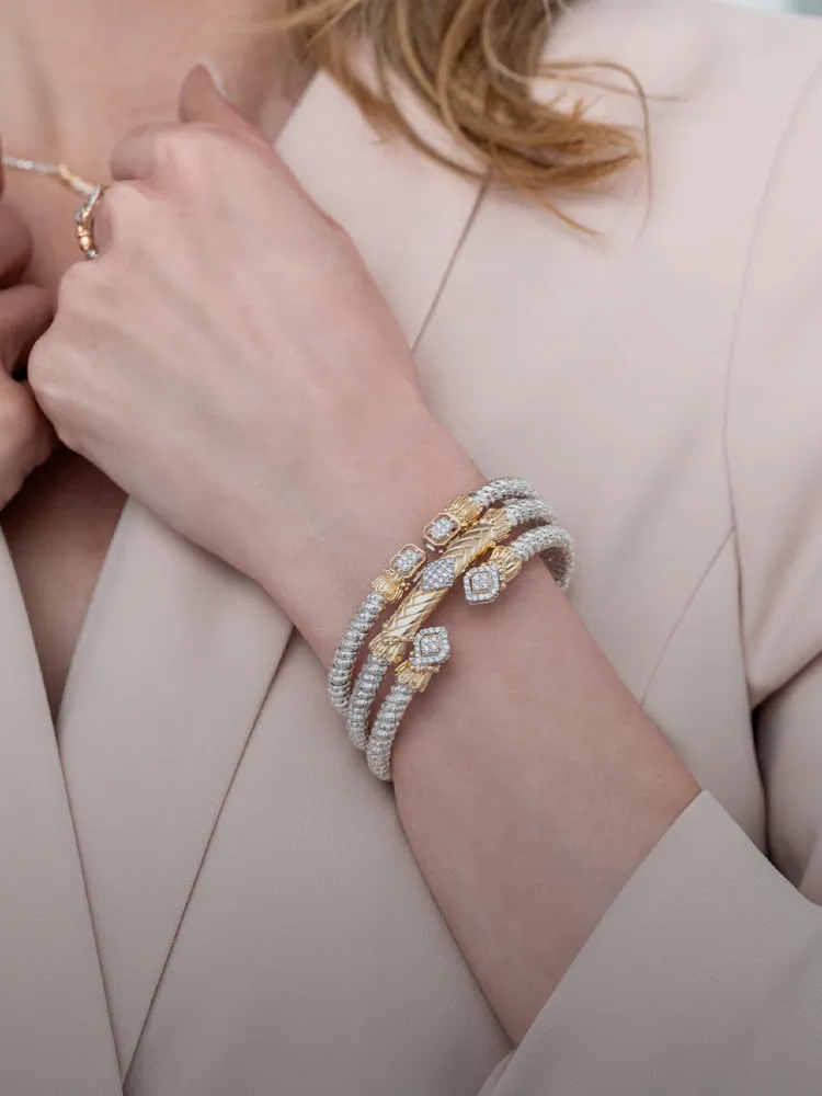 Elegant woman wearing multiple gold and pearl bracelets, promoting Bryan Jewelry's collection.