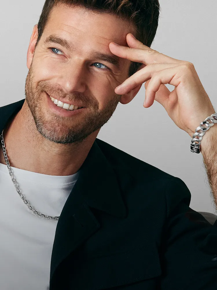 Man smiling while wearing a silver chain necklace and bracelet, promoting men's jewelry at Bryan Jewelry in Prattville.