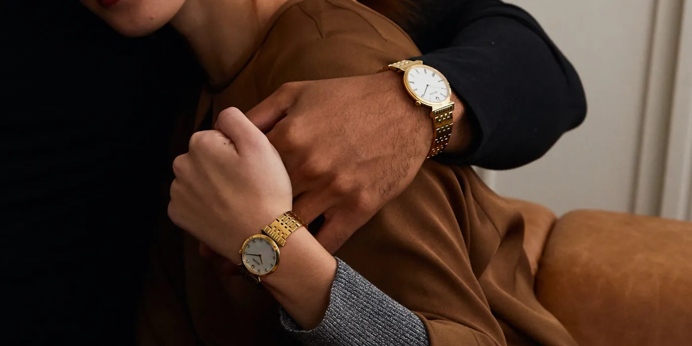 Couple showcasing matching gold watches, symbolizing love and connection. Visit Bryan Jewelry for fine jewelry in Prattville.