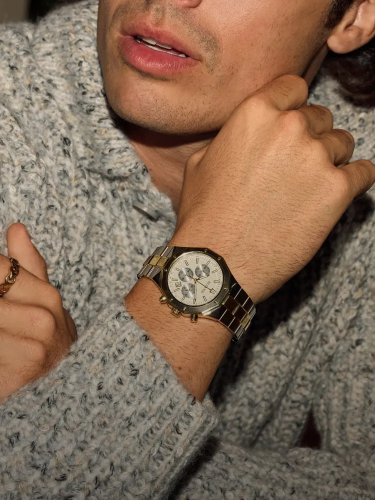 Man wearing a cozy sweater and a stylish gold watch, promoting Bryan Jewelry's watch collection. 