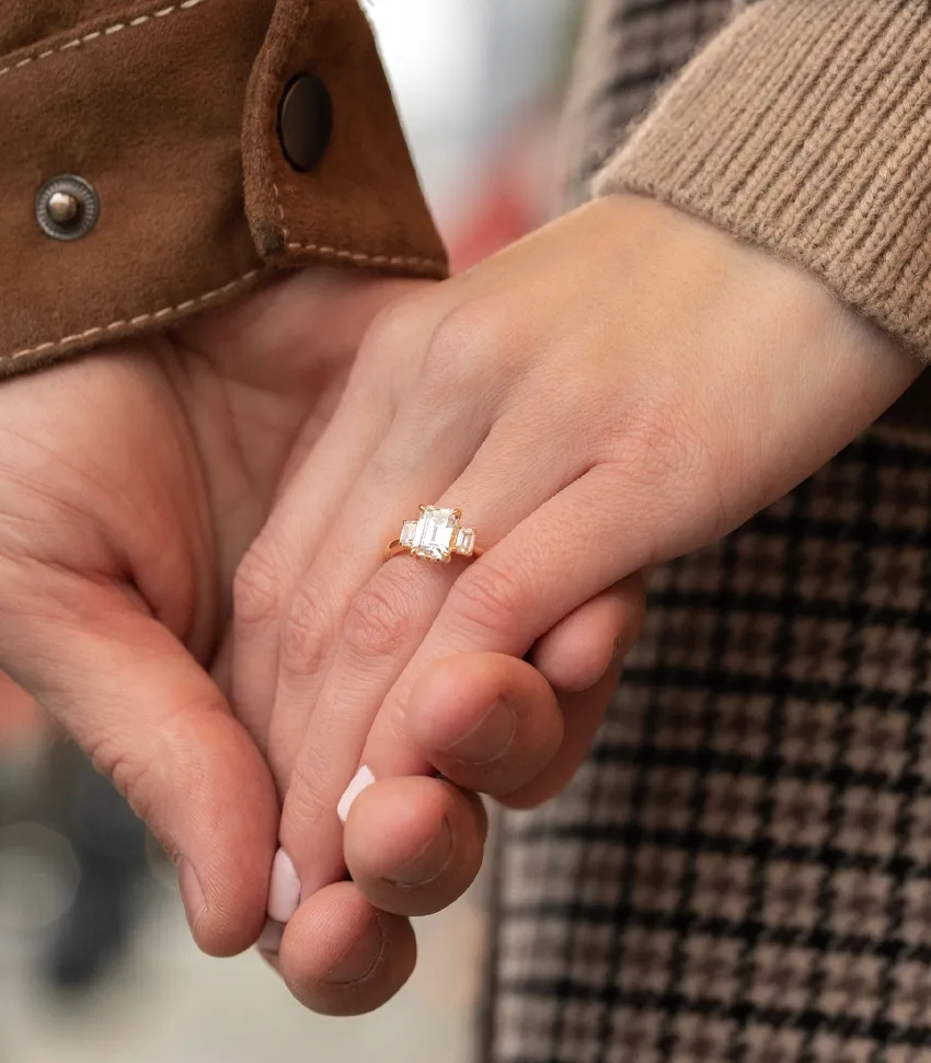 Engaged couple holding hands, showcasing an elegant engagement ring at Bryan Jewelry in Prattville.