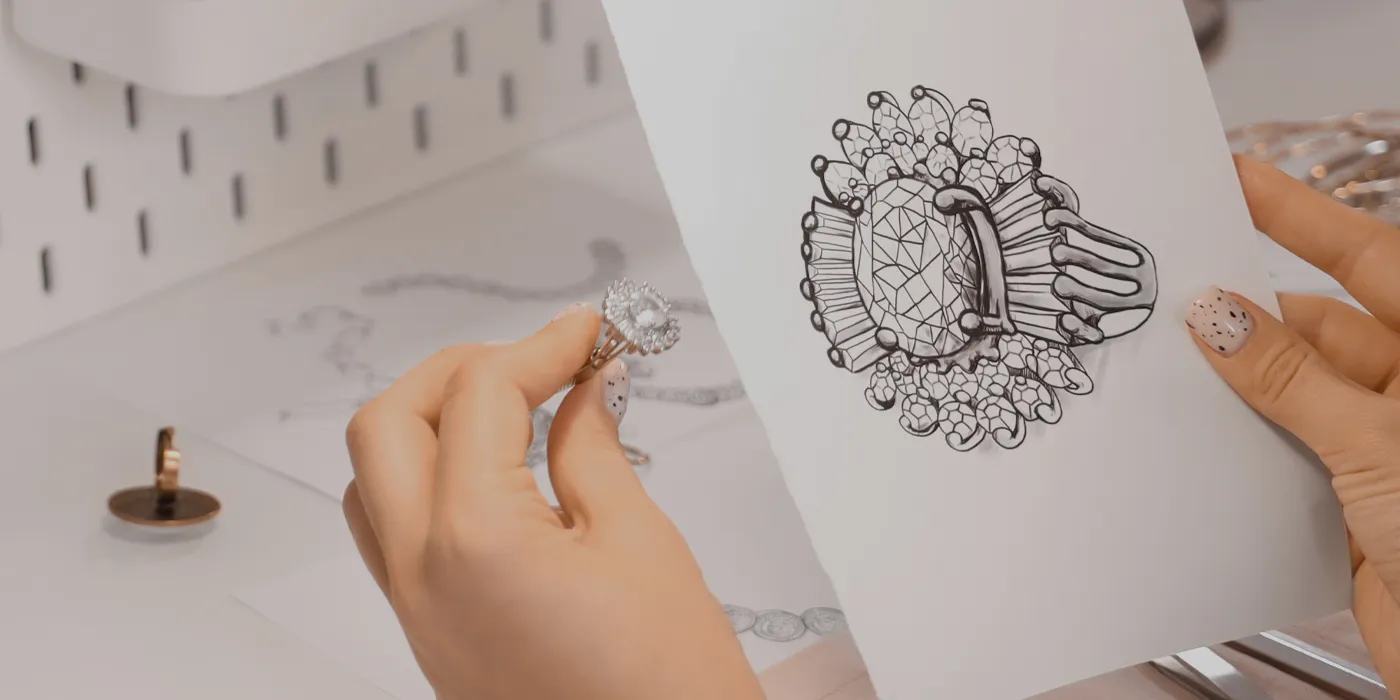 A hand holds a diamond ring next to a sketch of a similar design, showcasing jewelry design at Bryan Jewelry. Start a Project.