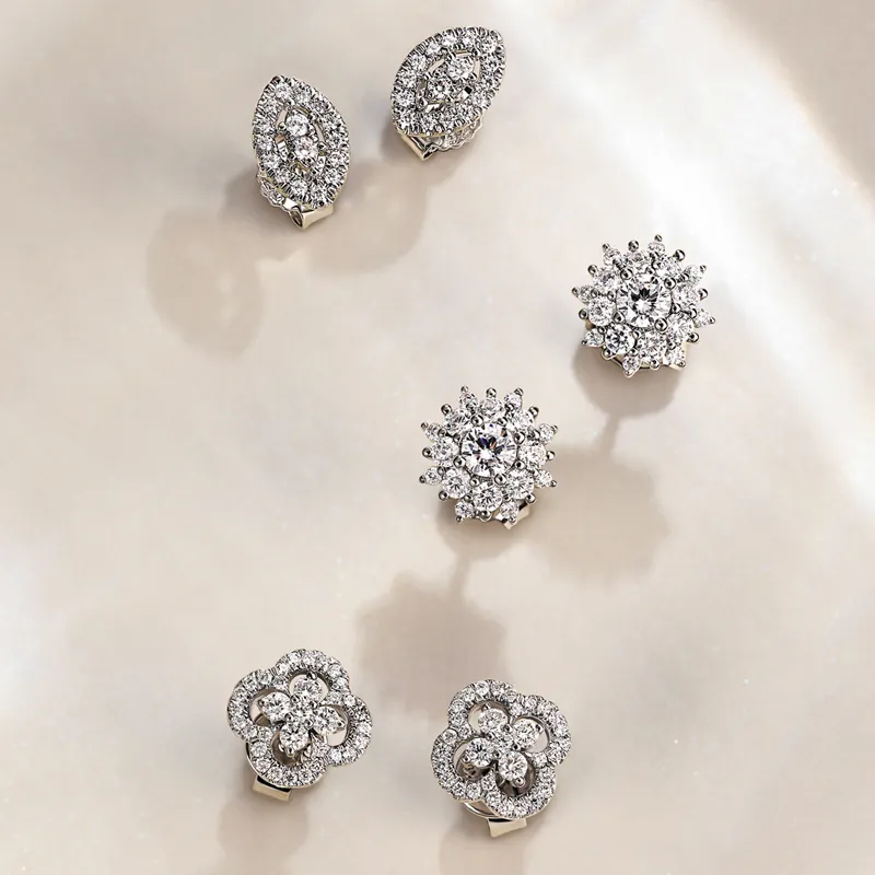 Six pairs of sparkling diamond earrings displayed on a soft surface, showcasing various elegant designs.