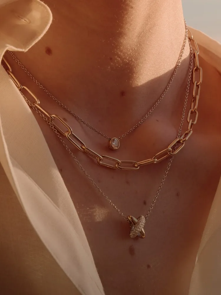 Layered gold and silver necklaces on a model's neck, showcasing elegant jewelry from Bryan Jewelry in Prattville.