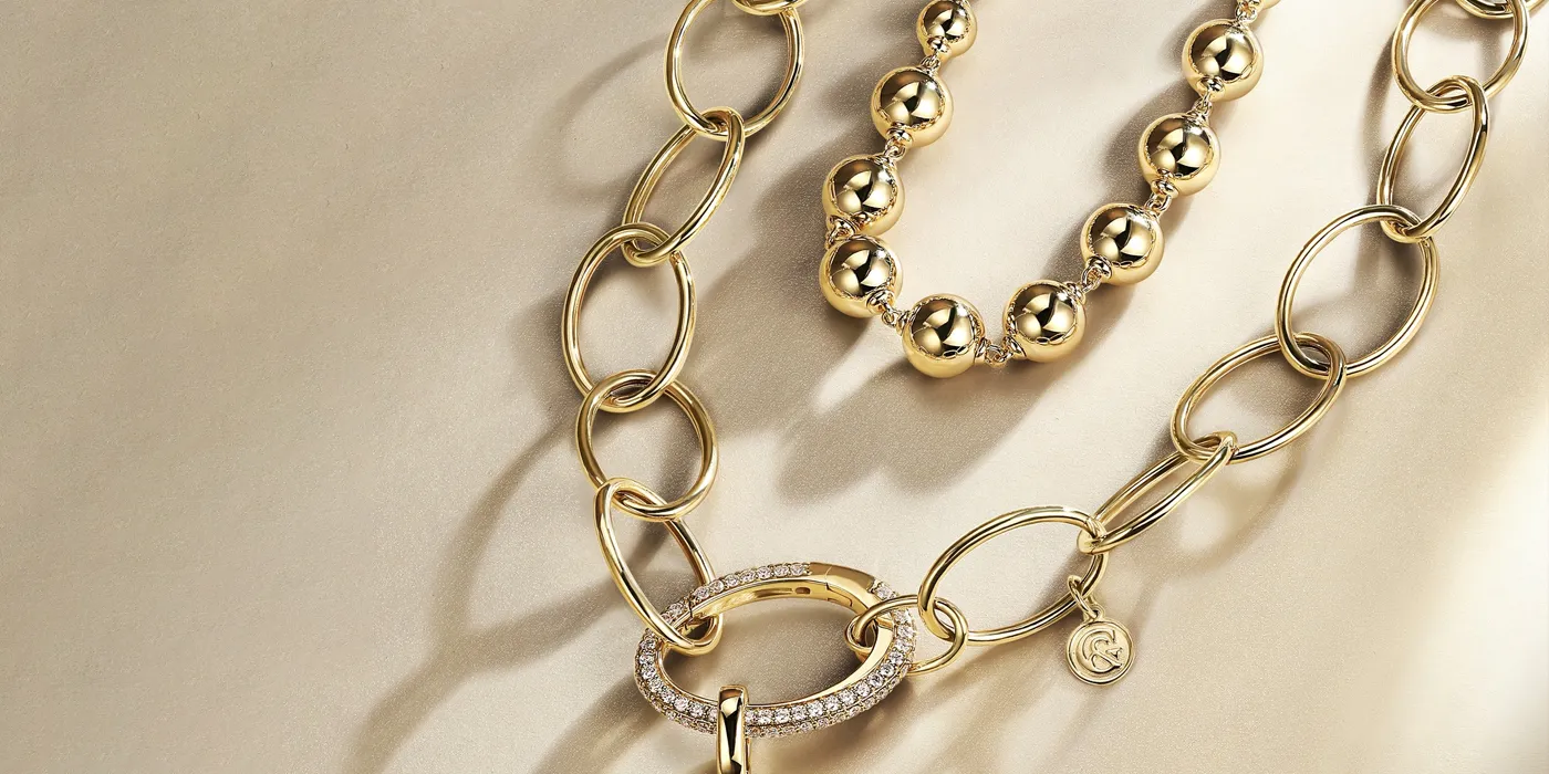 Gold necklaces with links and beads, featuring a diamond-encrusted clasp. Shop at Bryan Jewelry in Prattville.