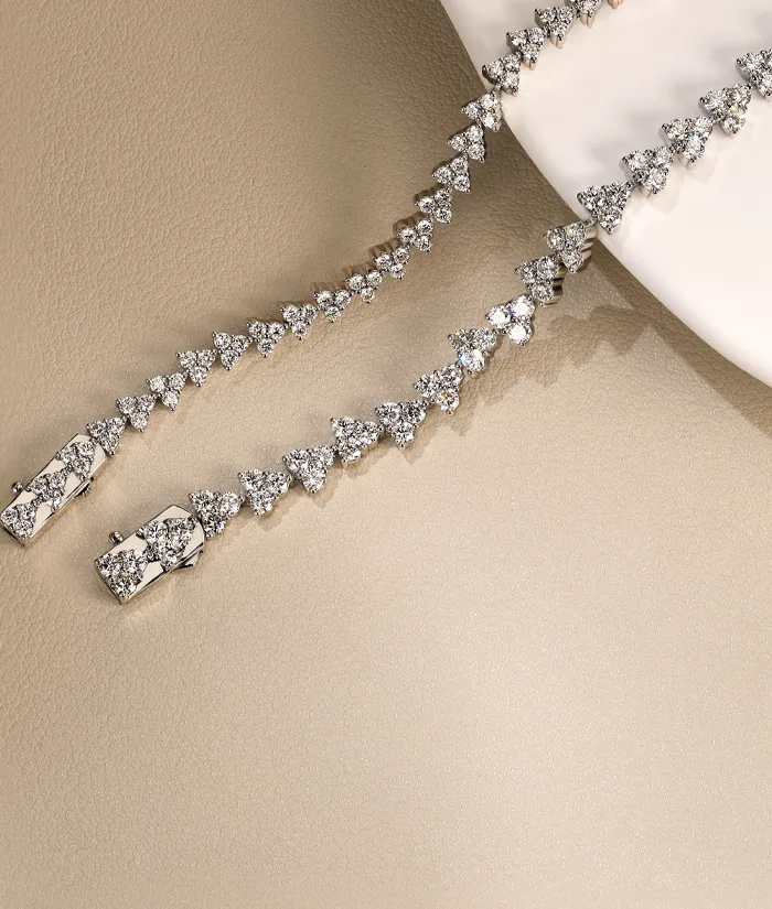 Elegant diamond tennis bracelet displayed on a soft beige surface. Click to Shop Classics at Bryan Jewelry.