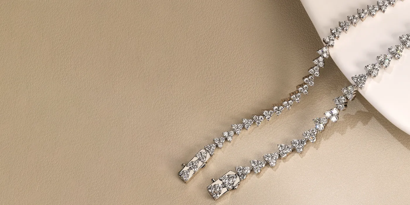 Elegant diamond tennis bracelet displayed on a soft beige surface. Click to Shop Classics at Bryan Jewelry.