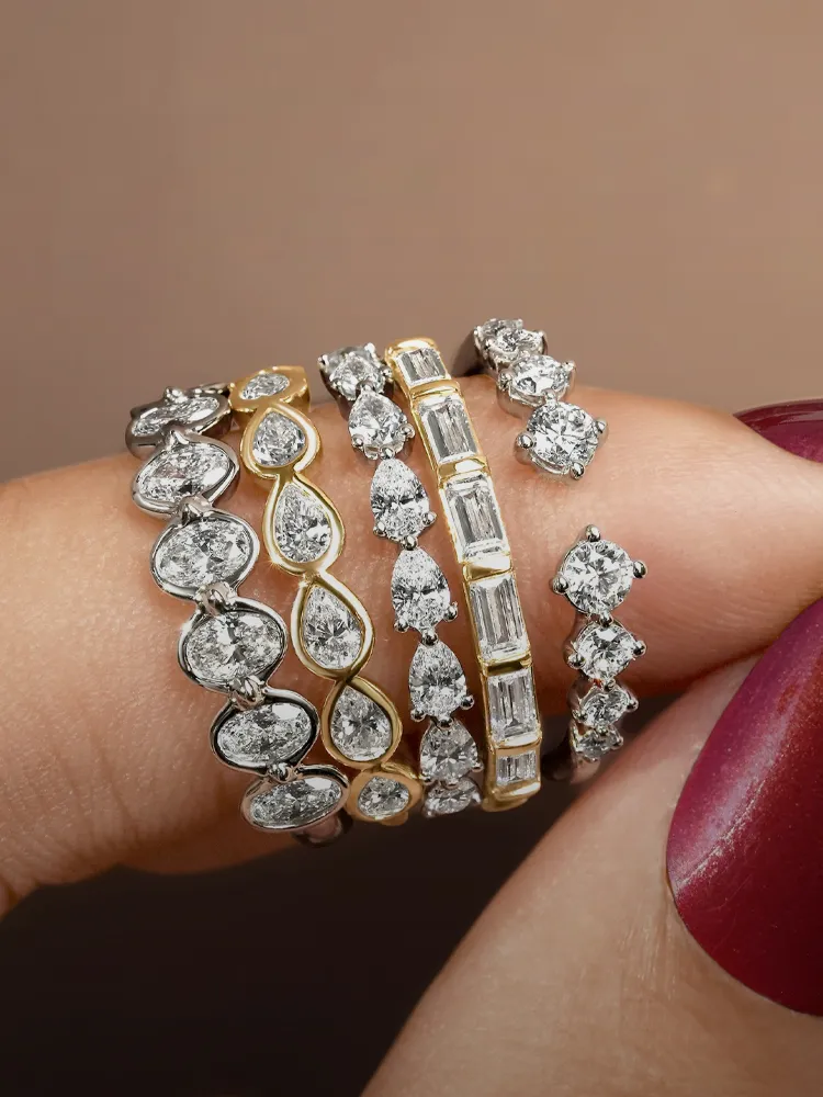 Five elegant diamond rings in various styles stacked on a hand, showcasing fine jewelry from Bryan Jewelry in Prattville.