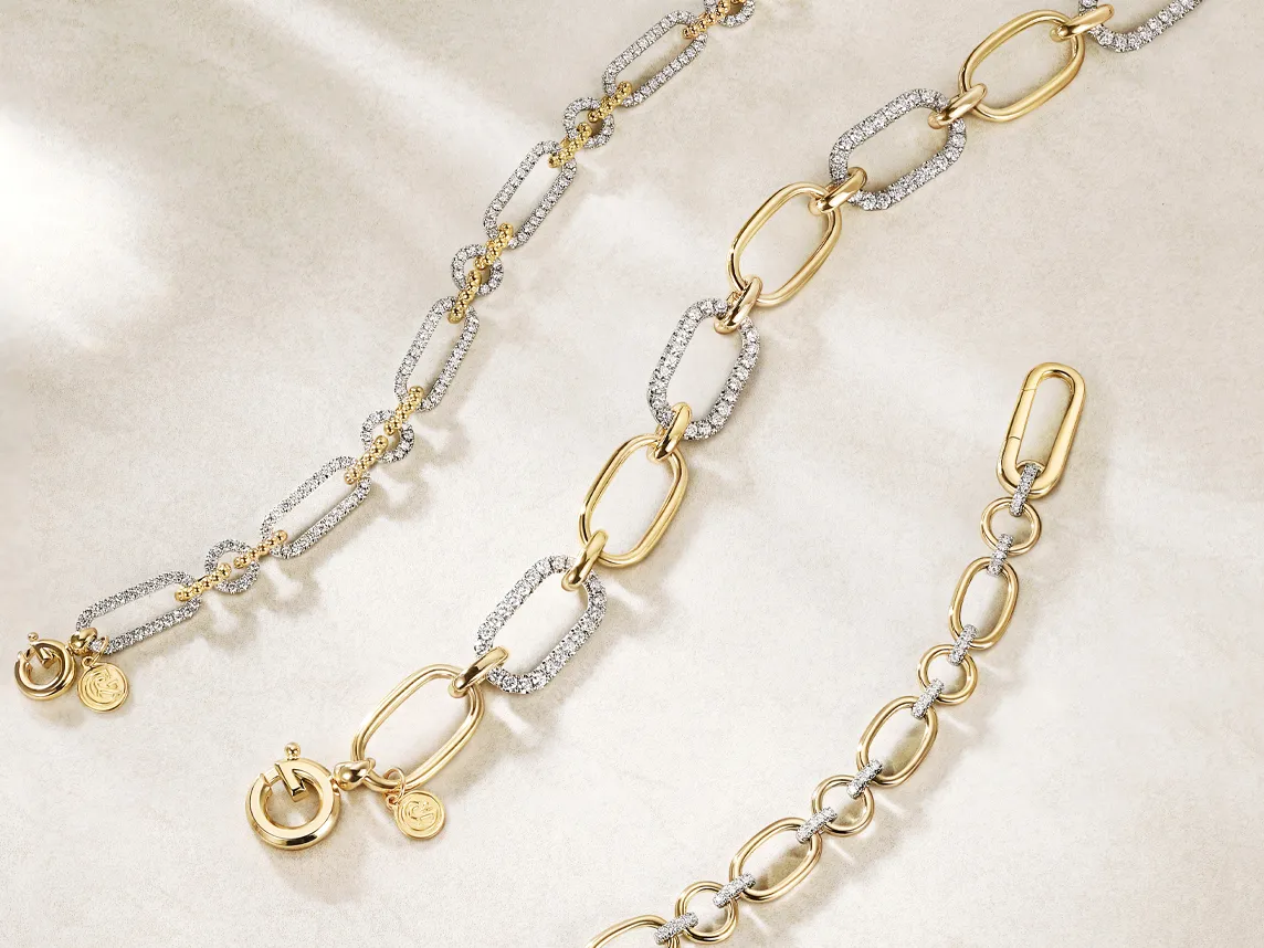 Three elegant gold and silver chain bracelets with sparkling accents displayed on a soft background. Shop at Bryan Jewelry.