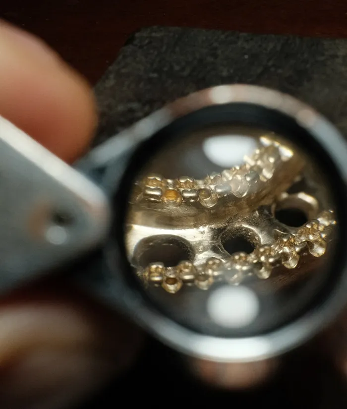 Close-up view of jewelry under magnification, showcasing intricate details of metalwork and gemstones.