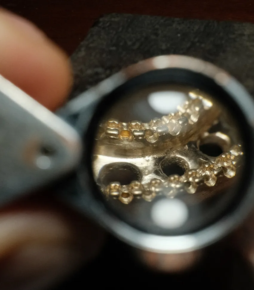 Close-up view of jewelry under magnification, showcasing intricate details of metalwork and gemstones.