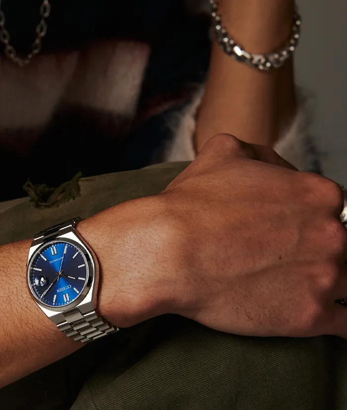 Close-up of a person's wrist wearing a blue dial Citizen watch with a silver bracelet. Shop fine jewelry at Bryan Jewelry.