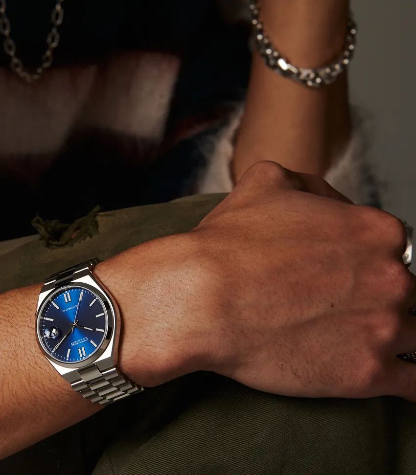 Close-up of a person's wrist wearing a blue dial Citizen watch with a silver bracelet. Shop fine jewelry at Bryan Jewelry.