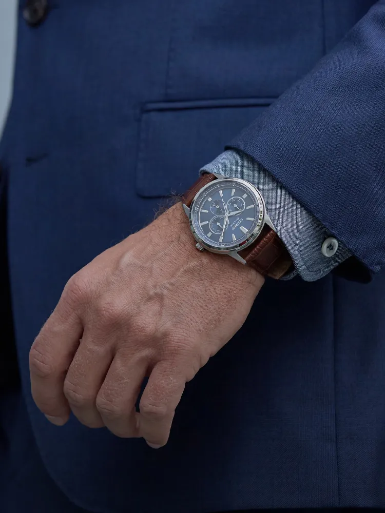 Stylish dress watch on a man's wrist, paired with a blue suit and light blue shirt. Shop at Bryan Jewelry in Prattville.