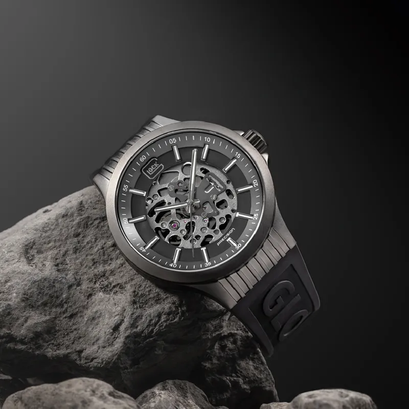 Stylish skeleton watch with a black strap, displayed on a rock against a dark background. Visit Bryan Jewelry for more.