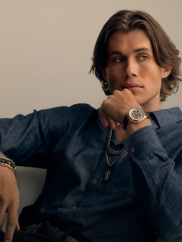 Stylish man in a denim shirt with accessories, showcasing a watch. Explore men's watches at Bryan Jewelry, Prattville.