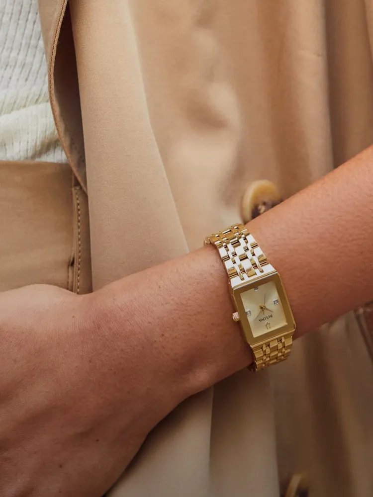 Gold sport watch on a wrist, paired with a beige outfit. Shop at Bryan Jewelry in Prattville for fine jewelry.