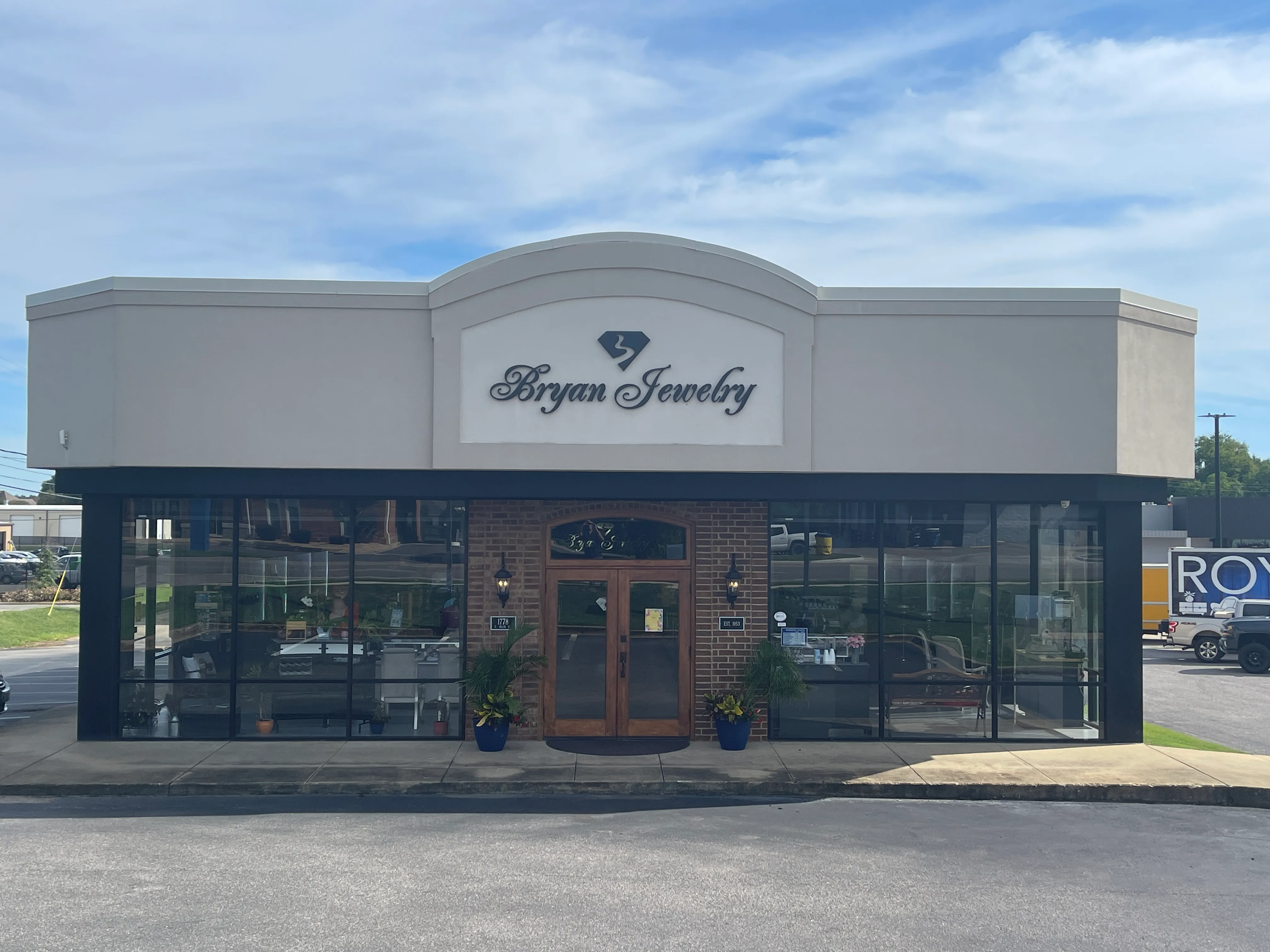 Interior of Bryan Jewelry store in Prattville, showcasing display cases filled with fine jewelry and a TV on the wall.