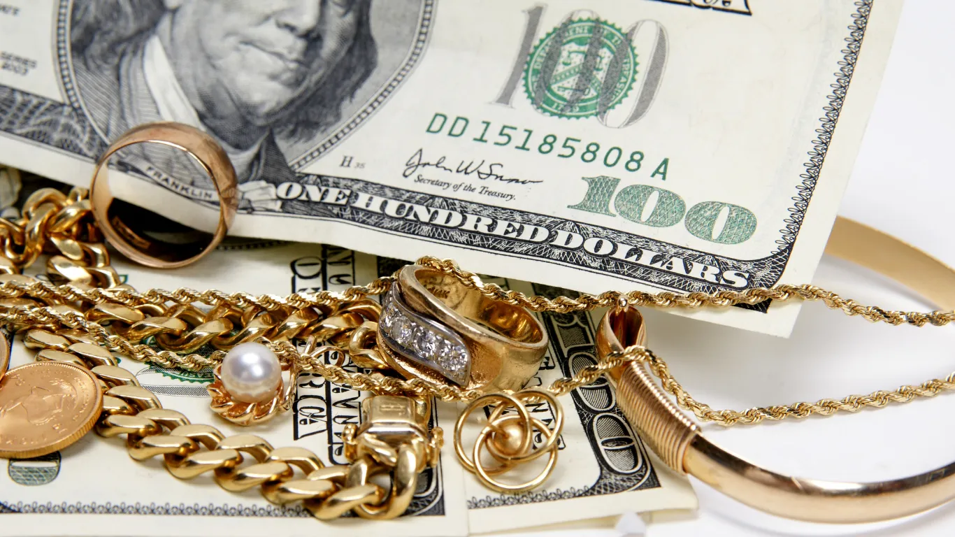 Gold jewelry and $100 bills arranged together. Visit Buchkosky Jewelers for more info on gold and diamond buying.