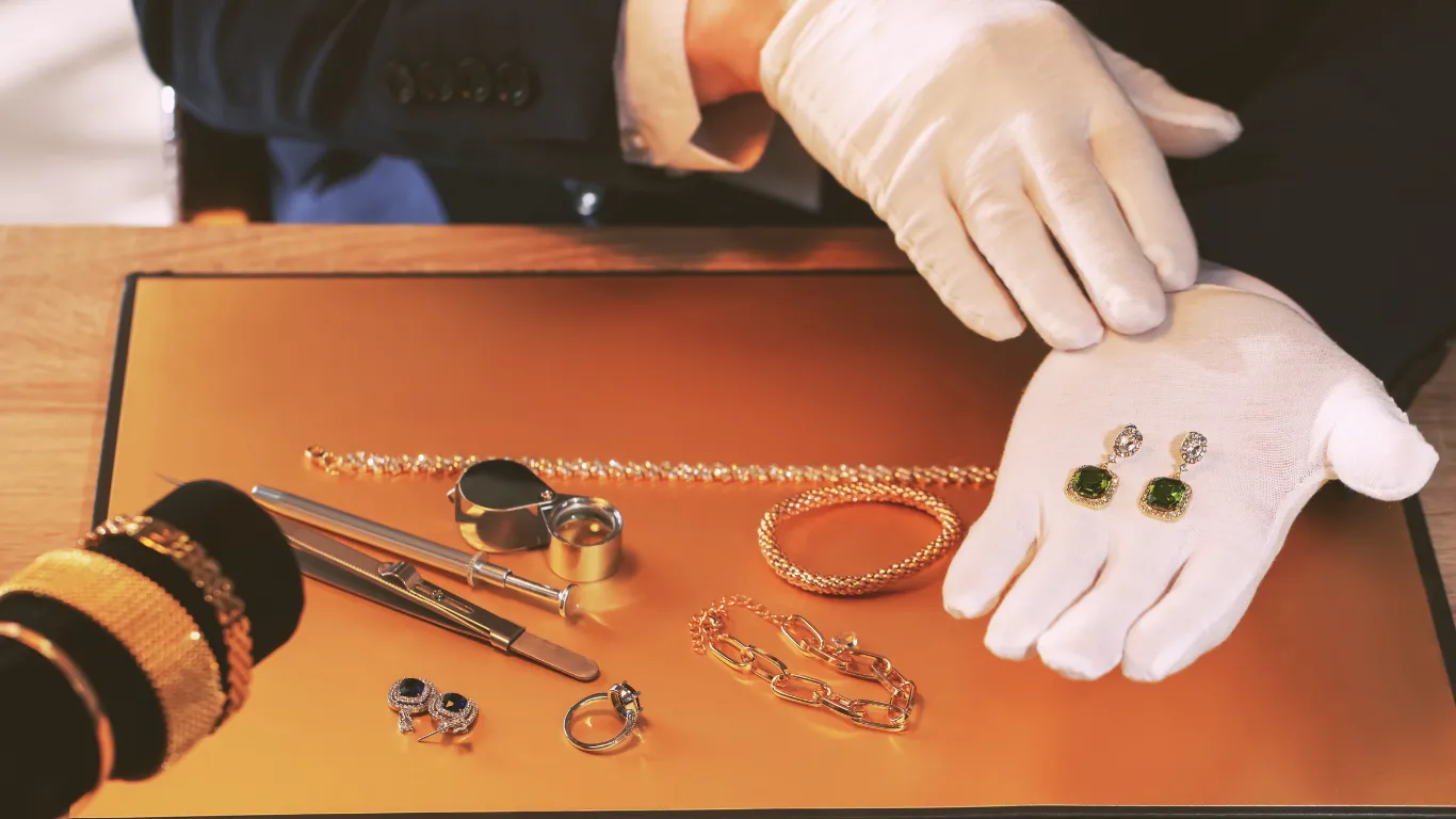 Jewelry display featuring green gemstone earrings, gold chains, and valuation tools at Buchkosky Jewelers, Inc.