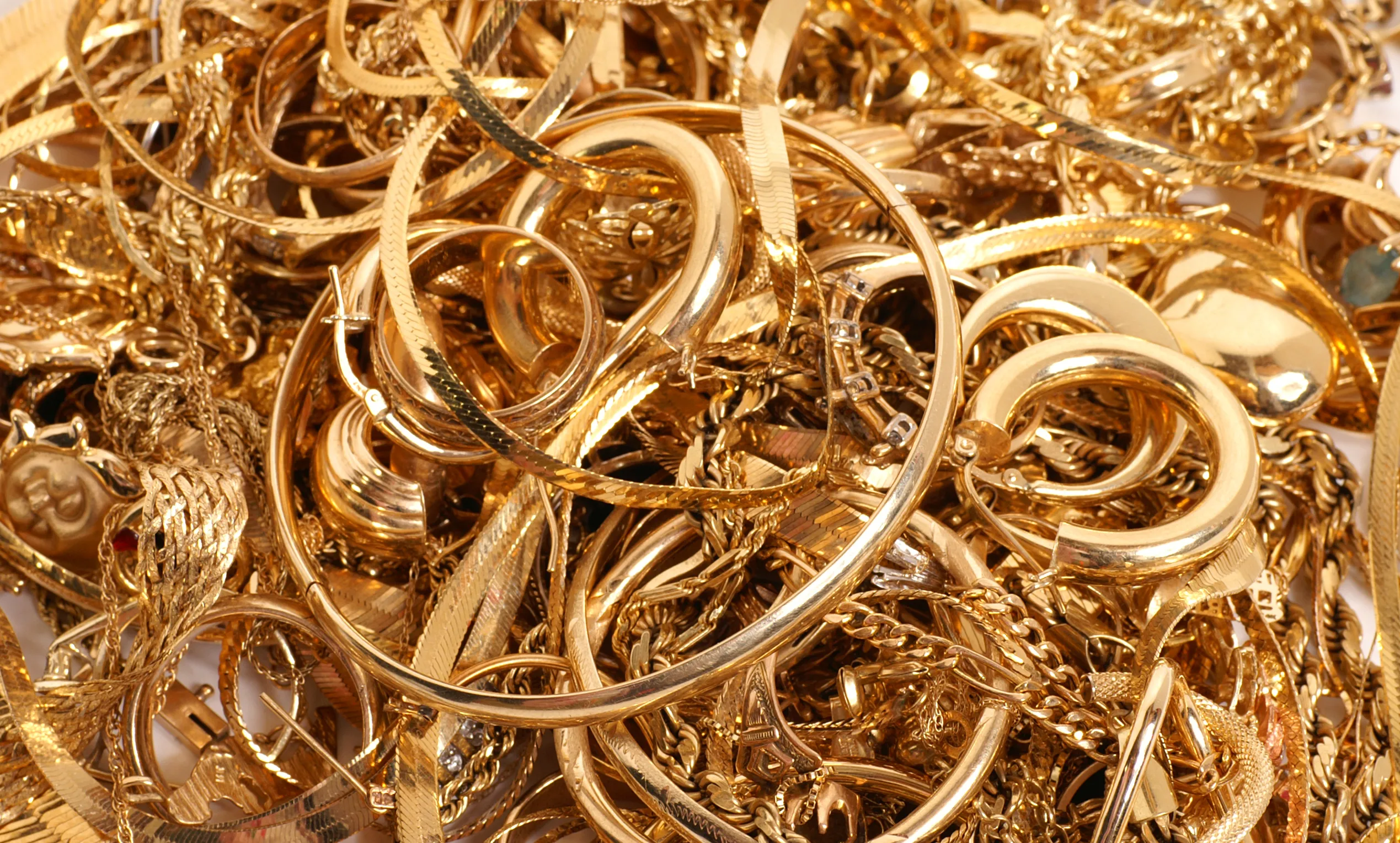 A pile of assorted gold jewelry including rings, chains, and pendants. Visit Buchkosky Jewelers for buying options.