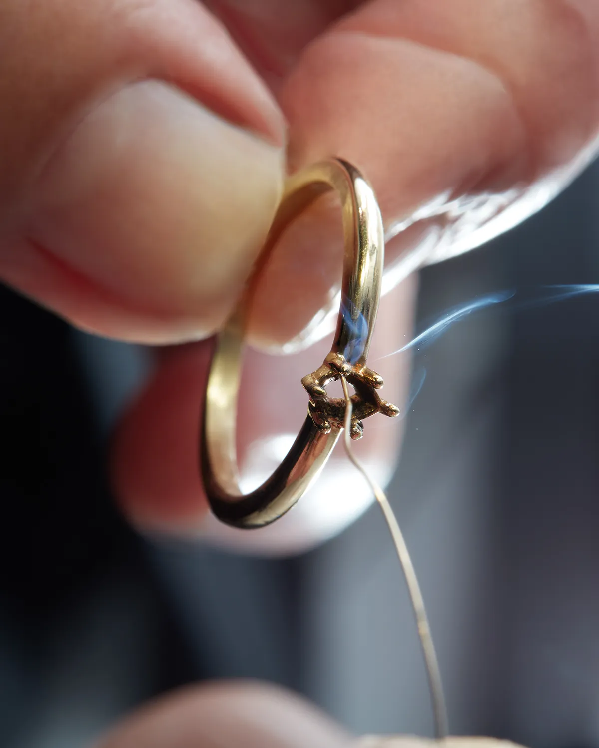 A person holding a gold ring with a small tool for repair. Learn more about in-store repairs.