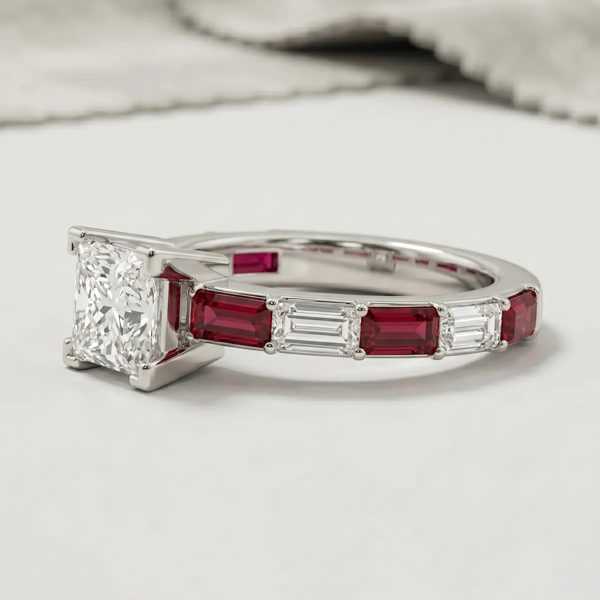 A diamond and ruby engagement ring with a square-cut center stone on a white surface.