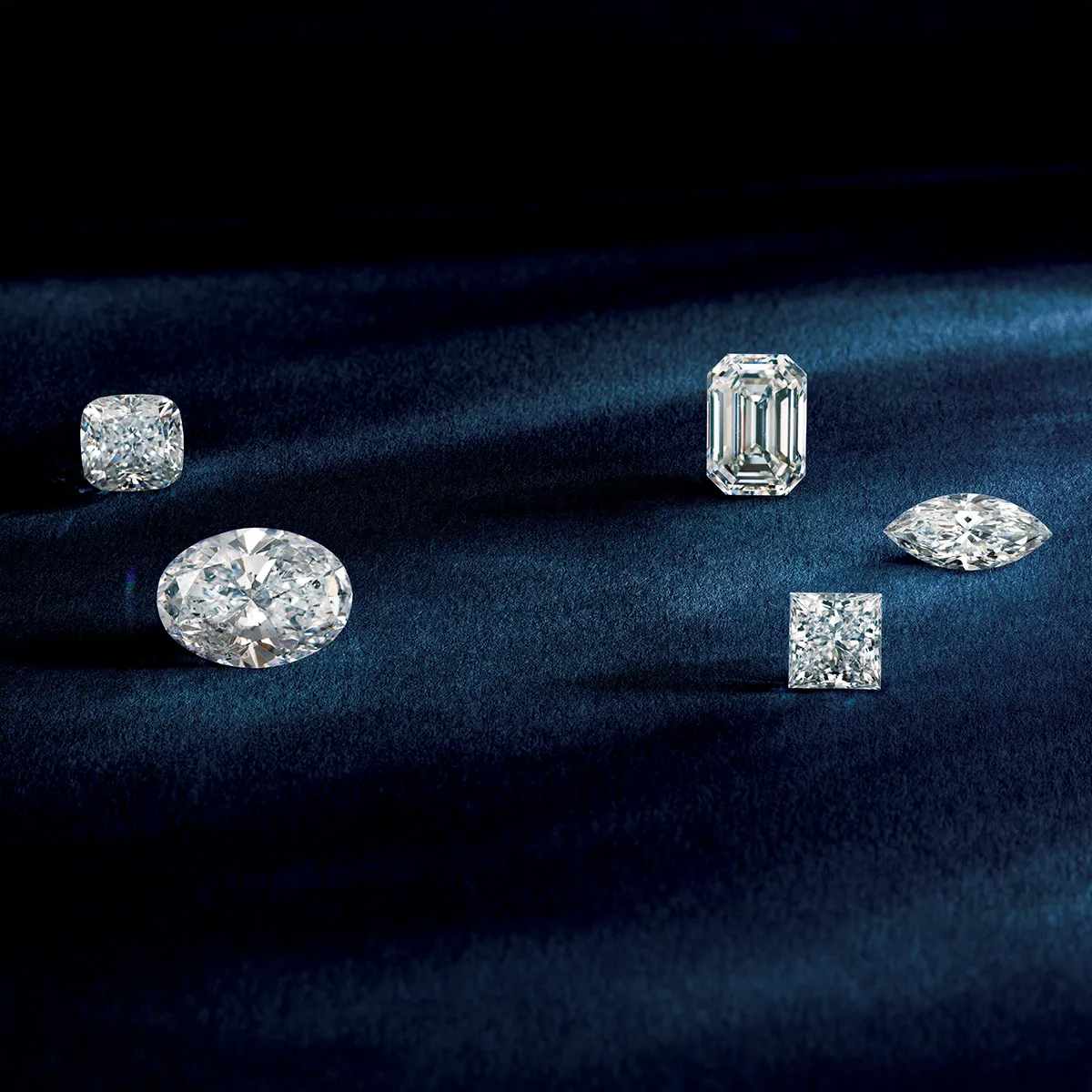Various diamond cuts displayed on a dark blue surface.