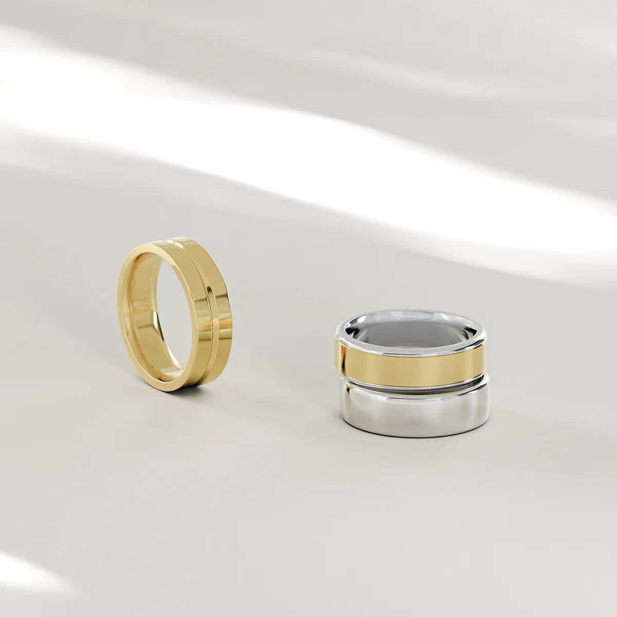 Two gold and silver men's wedding bands on a light surface.
