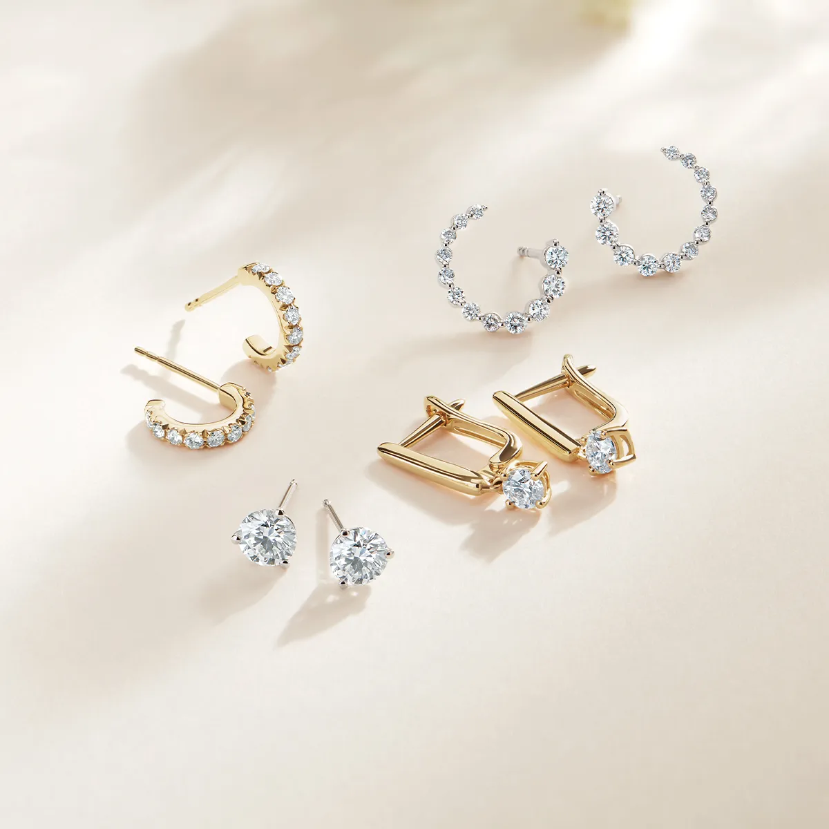 A selection of gold and diamond earrings displayed on a light background.
