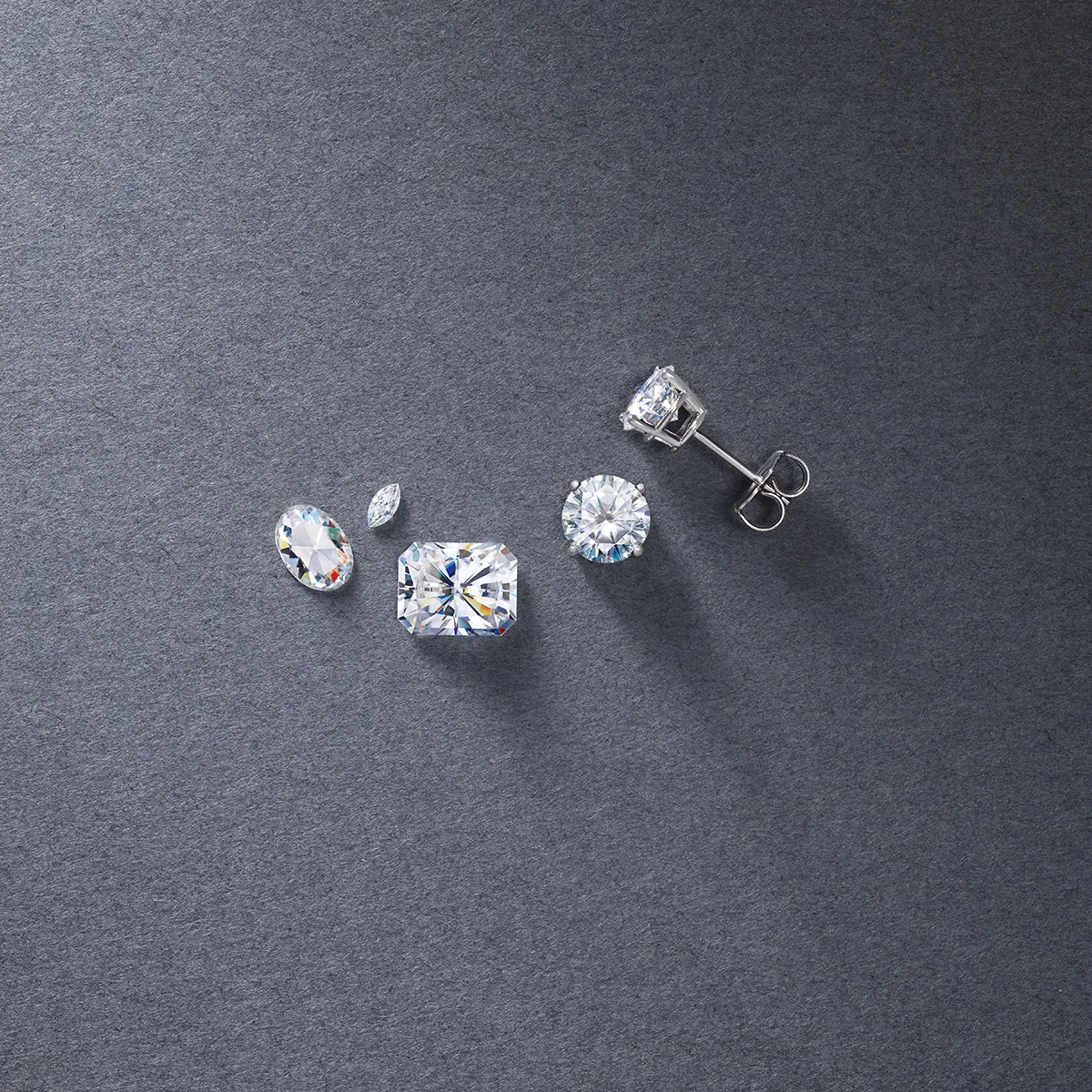 Lab-grown diamond studs and loose diamonds on a gray background.