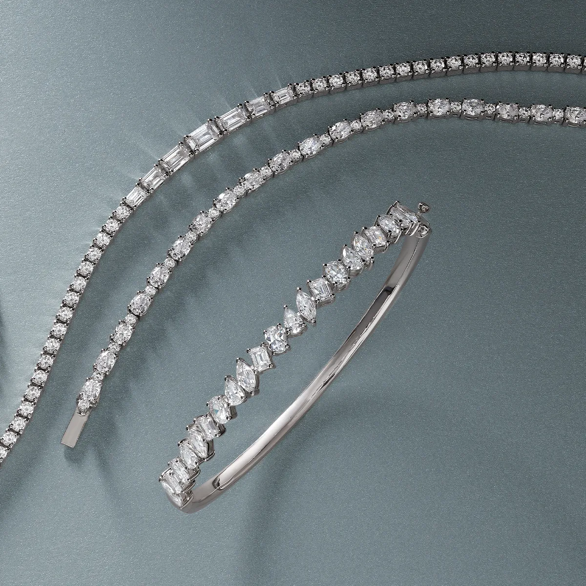 Elegant diamond bracelets displayed on a gray background.