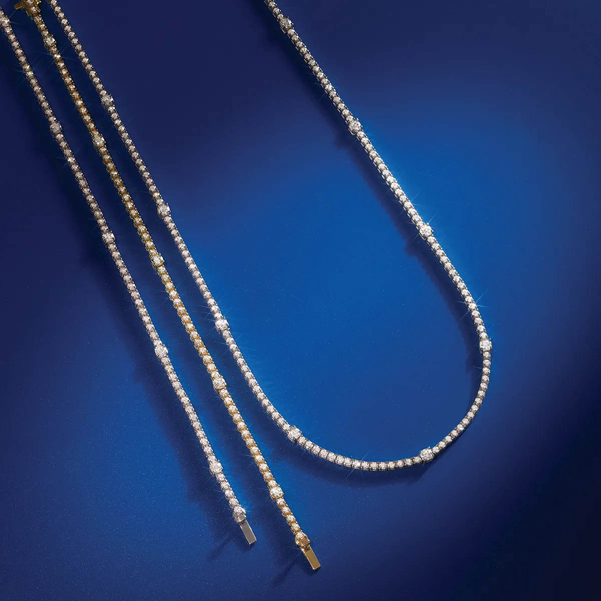 Elegant tennis necklaces with sparkling diamonds on a blue background.