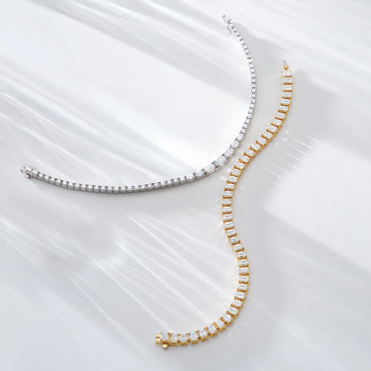 Two elegant tennis bracelets, one silver and one gold, displayed on a light background.