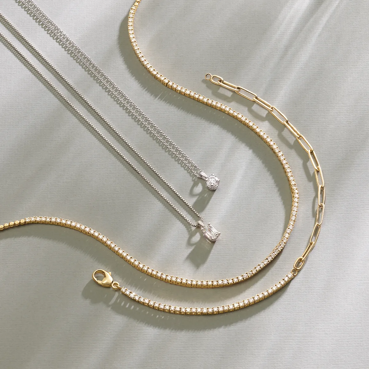 Elegant gold and silver necklaces with pendants displayed on a light background.