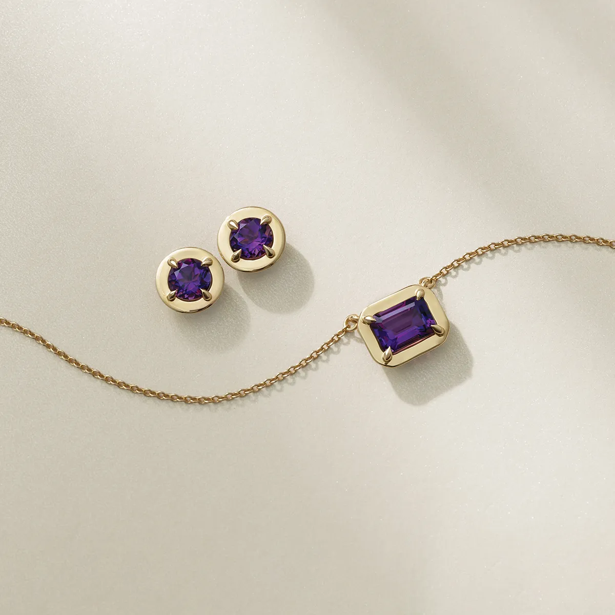 Gold amethyst earrings and necklace set on a light background.