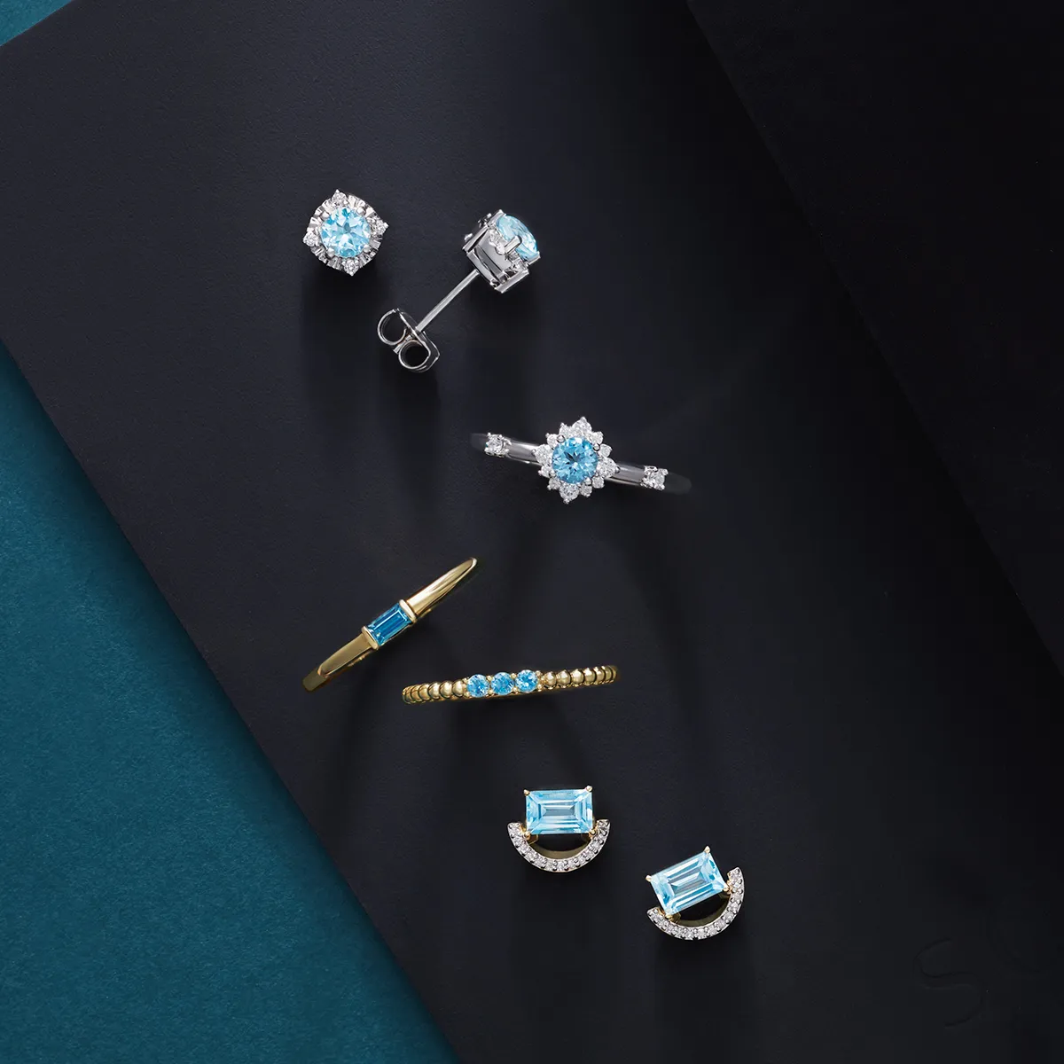 Aquamarine jewelry set including earrings, rings, and a bracelet on a dark background.