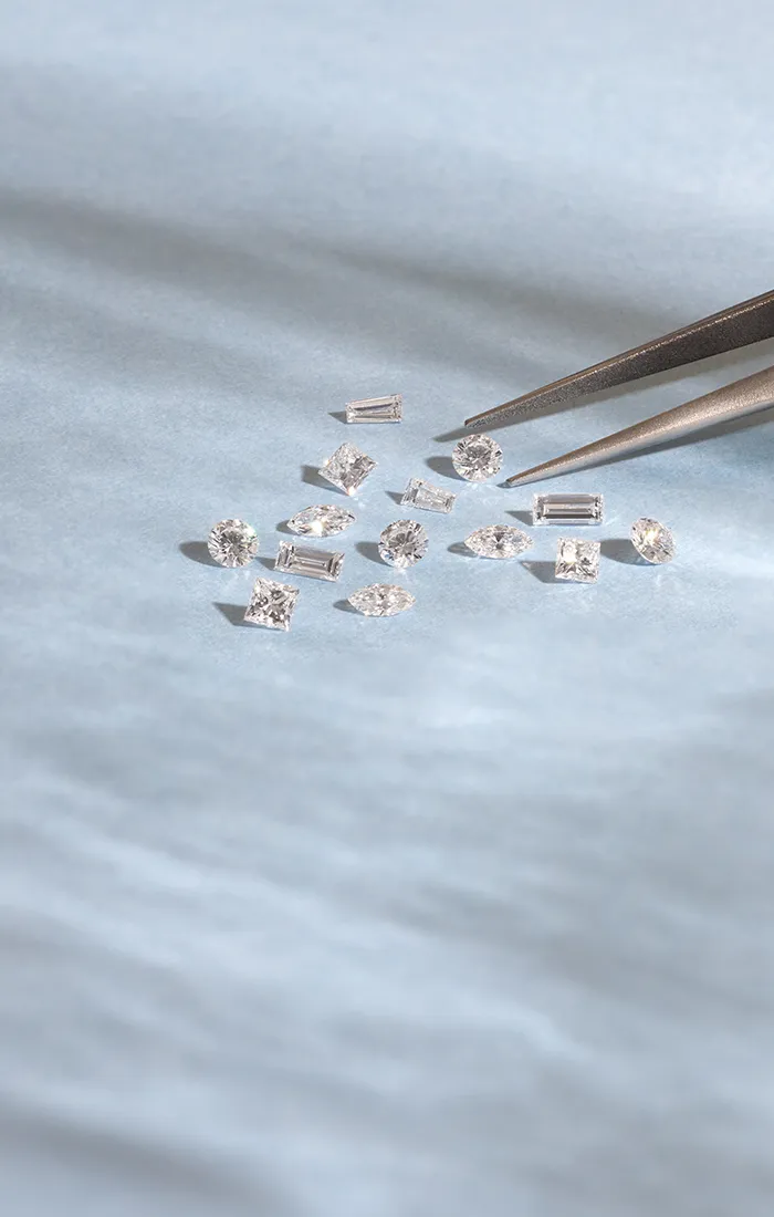 Small diamonds on a light surface with tweezers. Click to make an appointment.