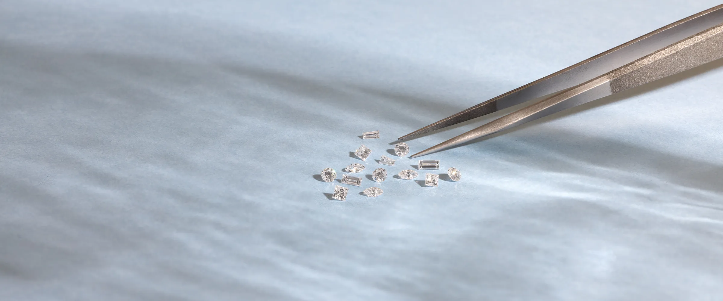Small diamonds on a light surface with tweezers. Click to make an appointment.