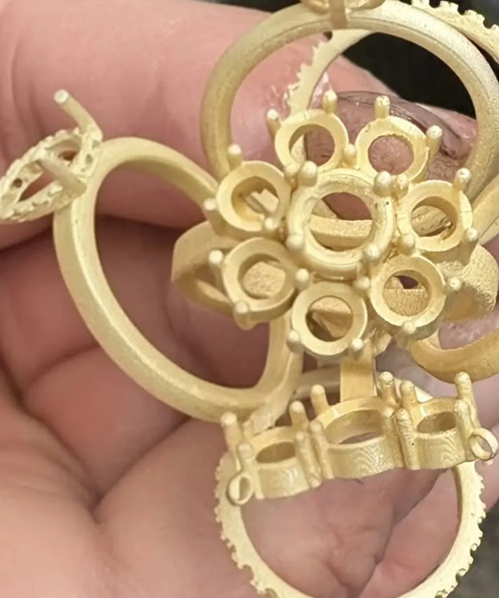Intricate gold jewelry piece with circular and floral patterns held in hand.