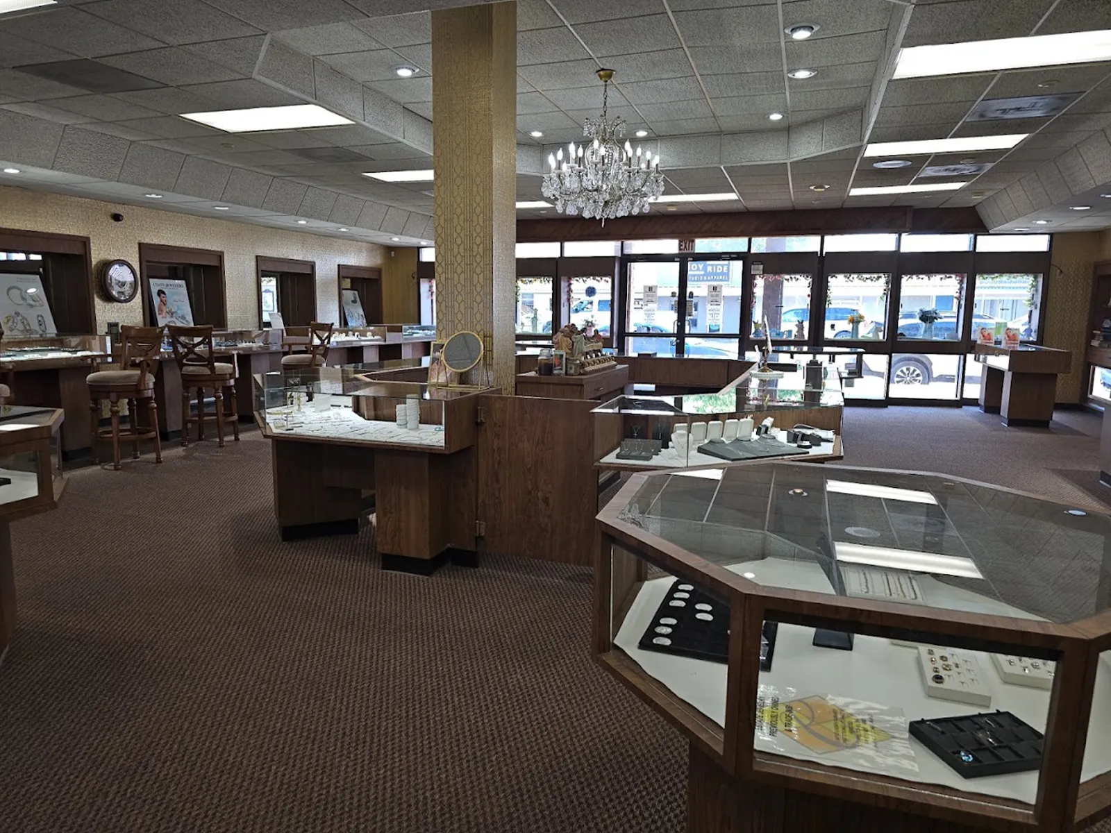 Spacious jewelry store interior with display cases, wooden decor, and a chandelier.