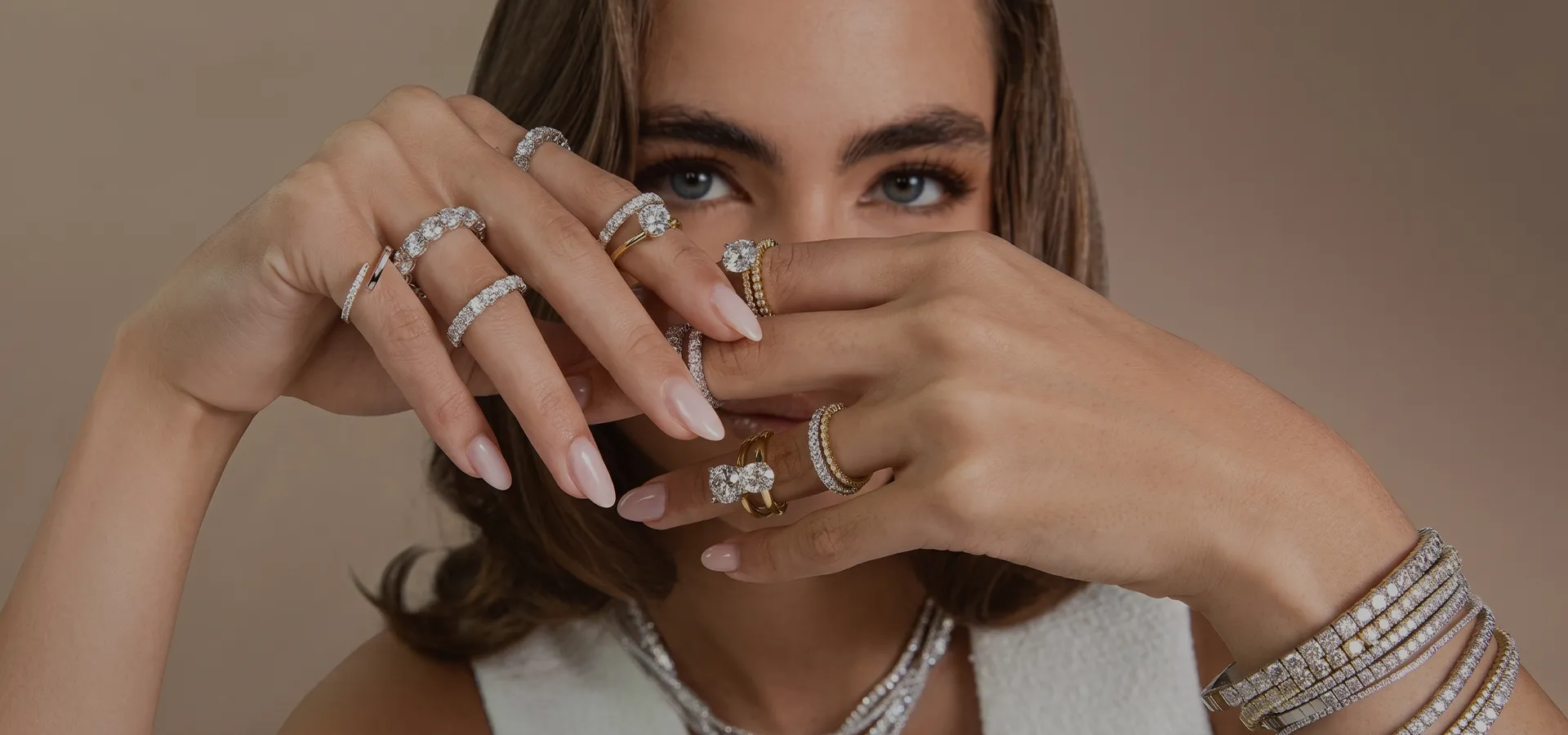 A woman displays multiple diamond rings and bracelets on her hands, with a focus on the jewelry.