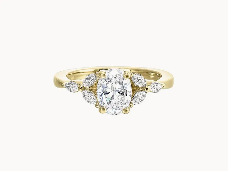 A gold ring with an oval diamond center and marquise side stones.