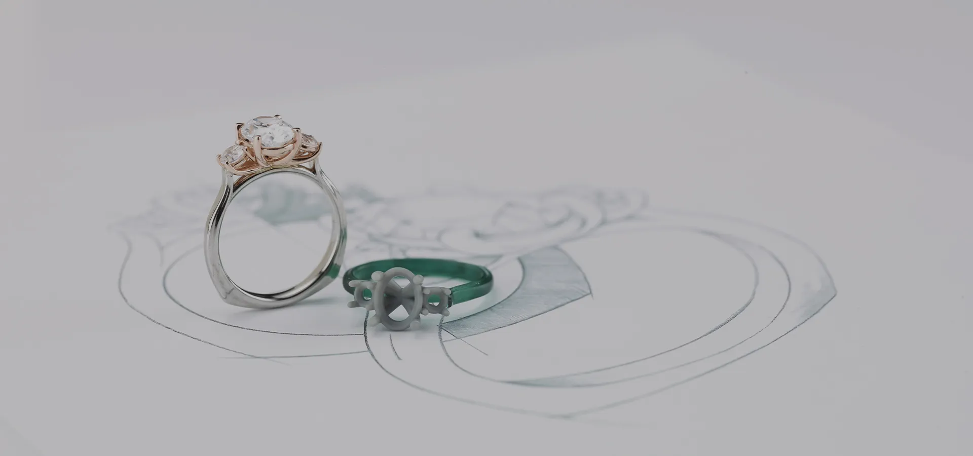 A diamond ring and a wax ring model on a jewelry design sketch.